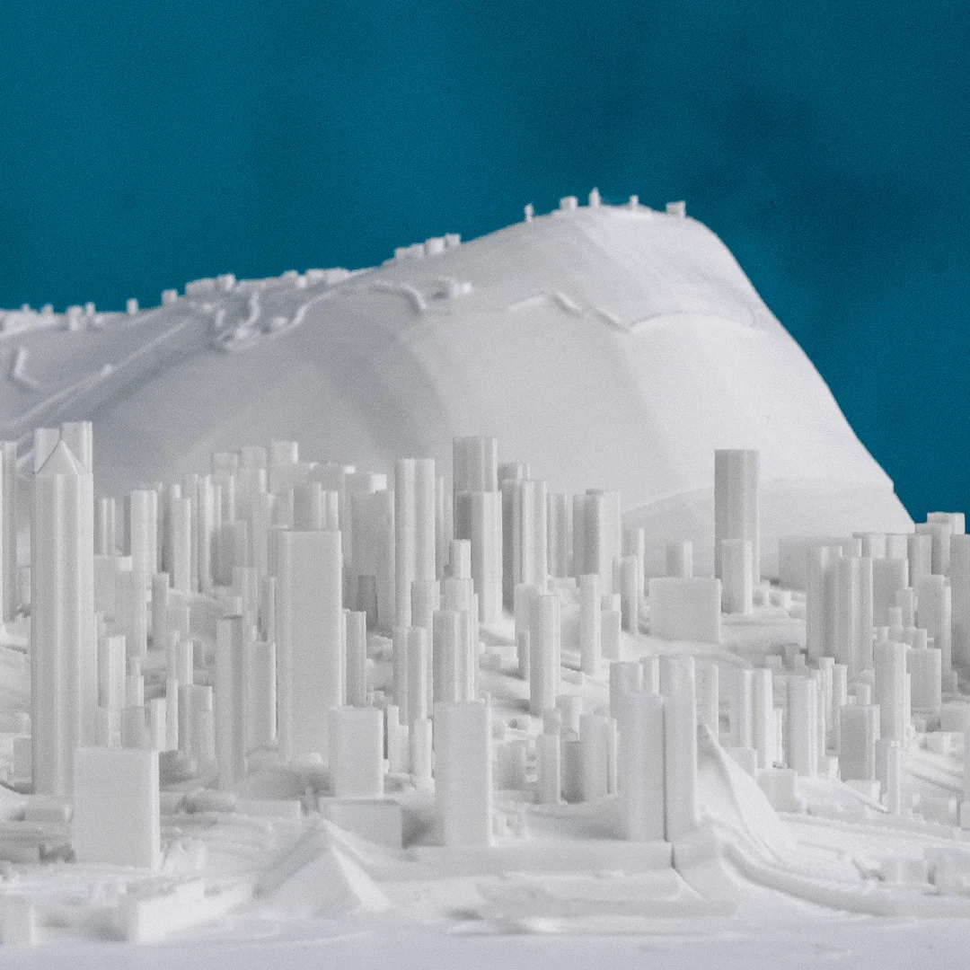 Low angled view of a Hong Kong city relief map showing towers beneath hillside terrain.