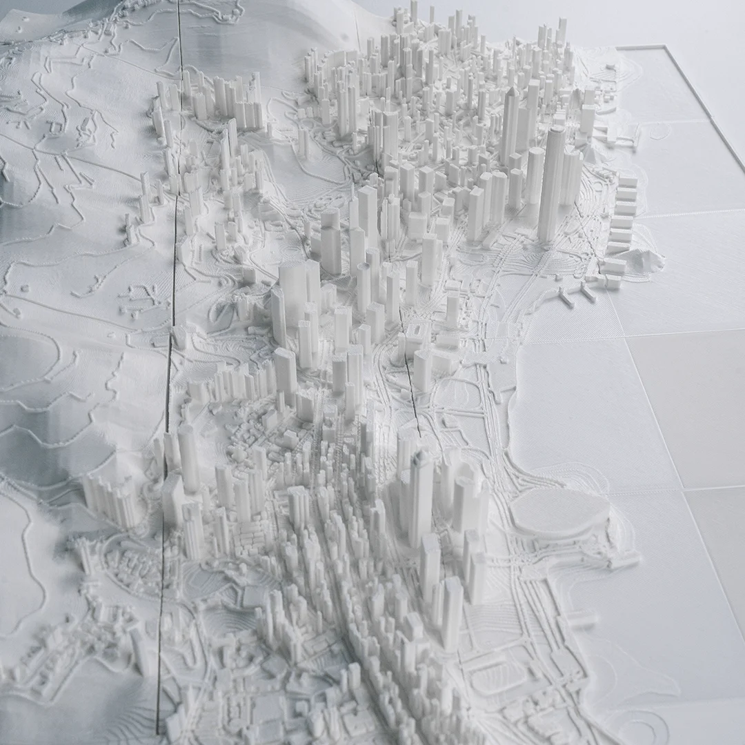 Overhead angled view of a Hong Kong relief map showing the waterfront and city blocks.