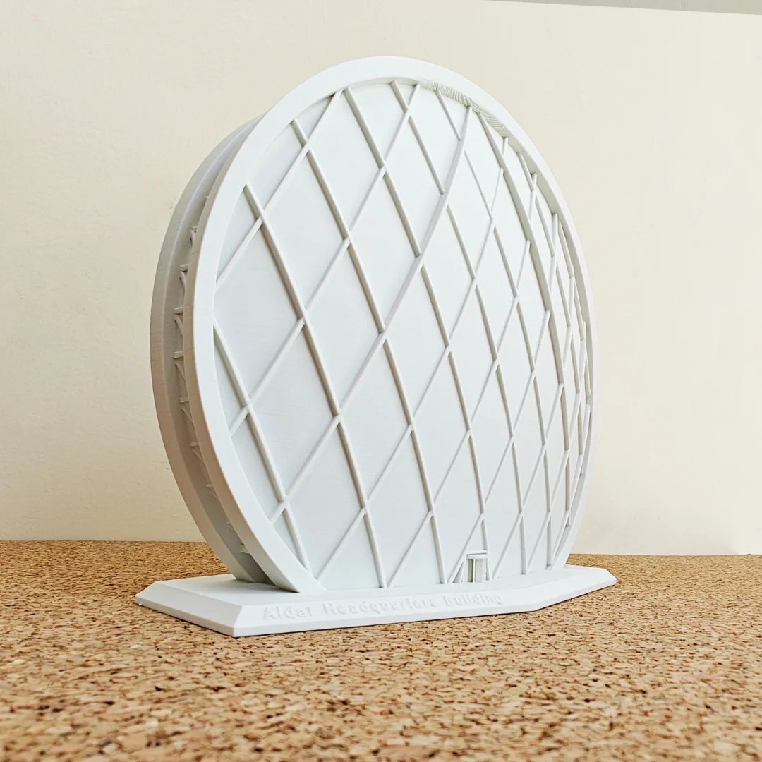 Angled view of an Aldar Headquarters model showing its circular facade and diagonal lattice.