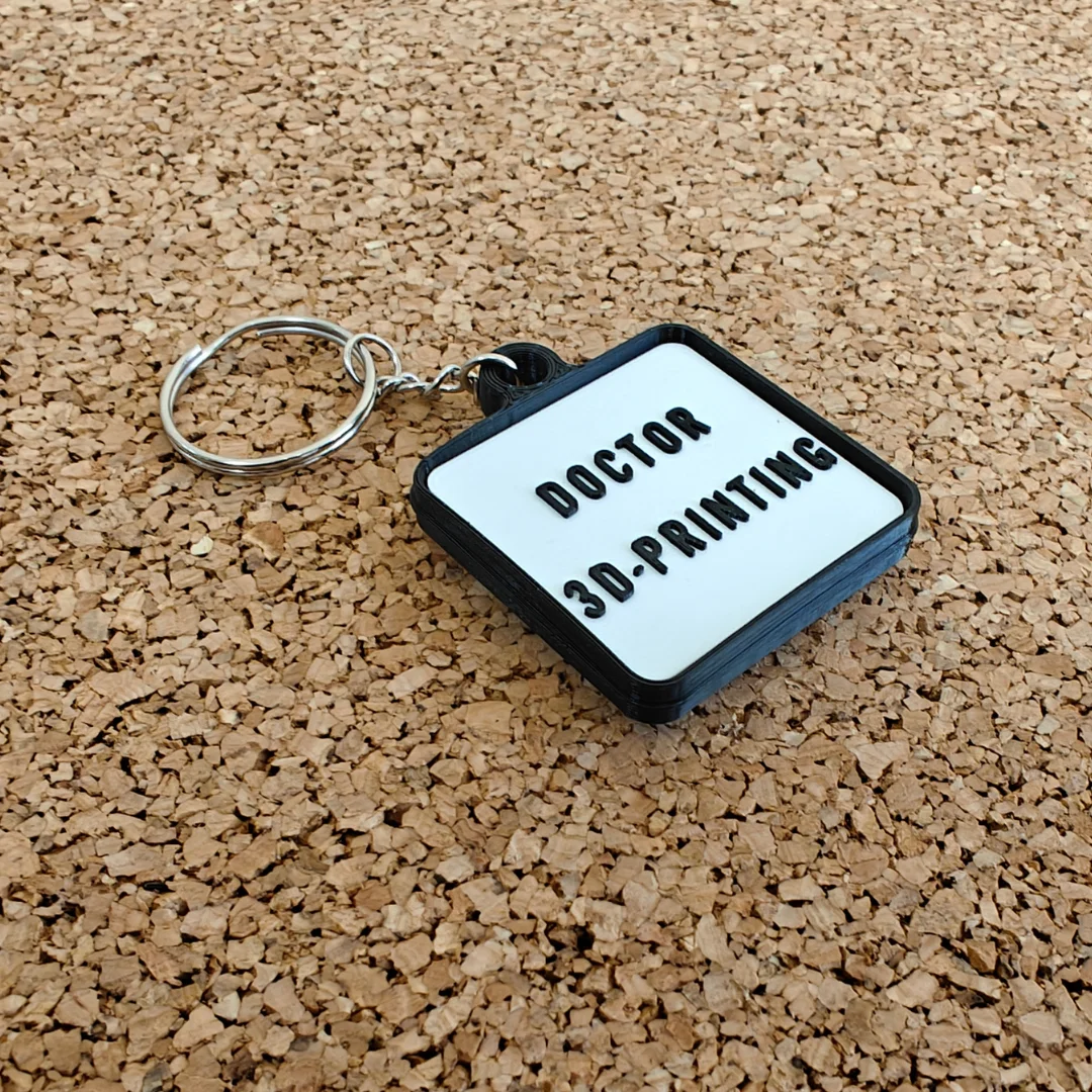 Reverse of the round pill keychain showing raised custom lettering.