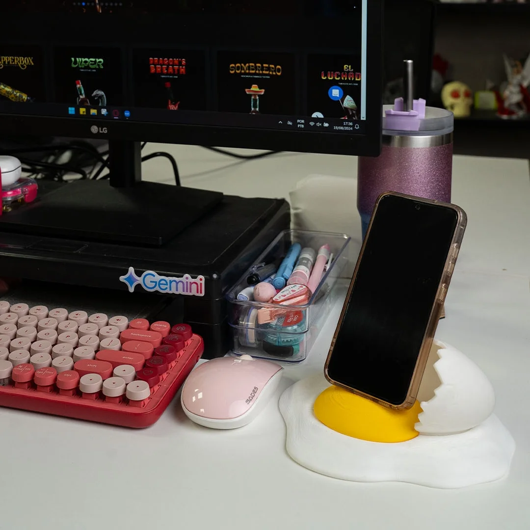 Broken egg phone holder supporting a smartphone on a desk.