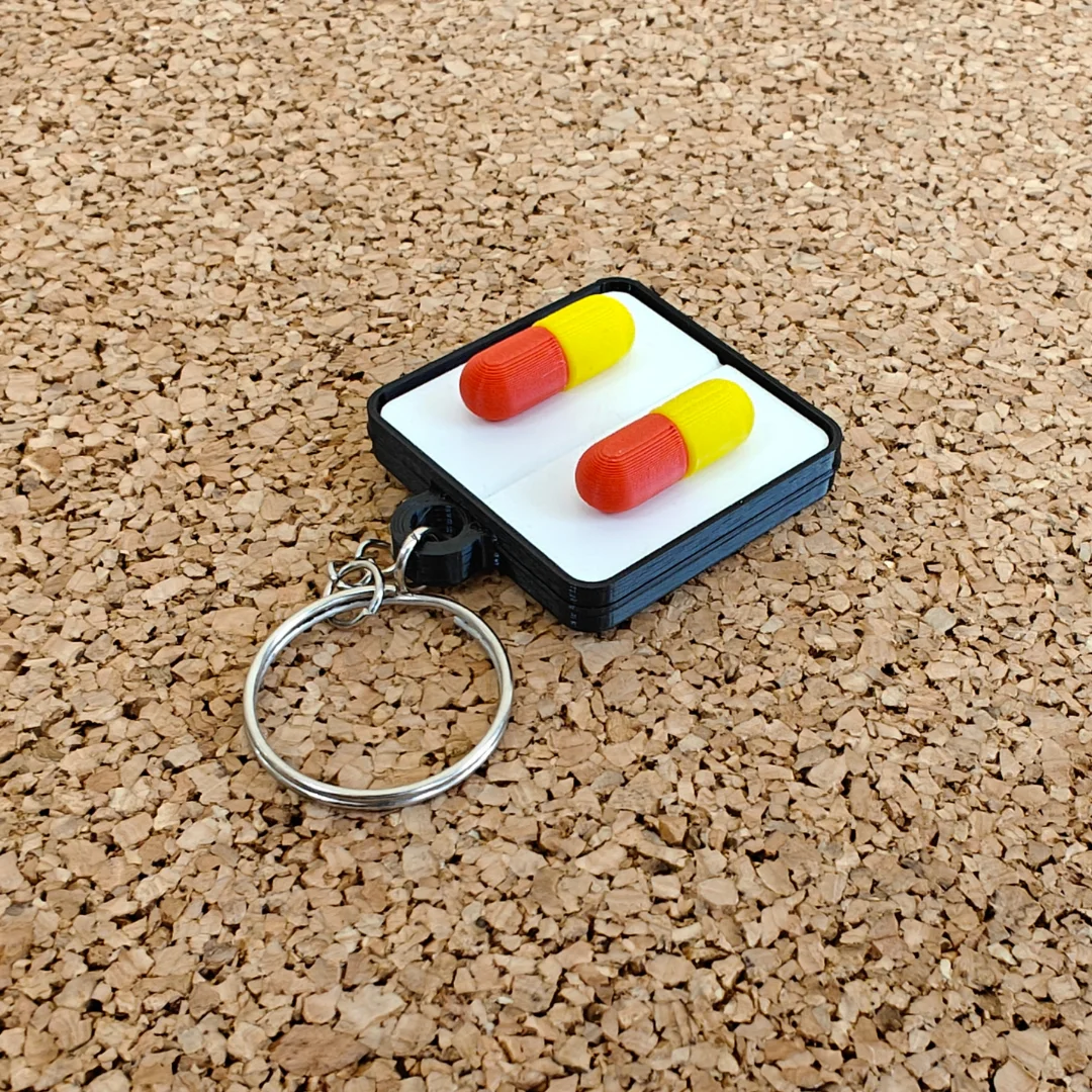 Angled view of a rectangular keychain with two raised capsule shapes and a metal split ring.