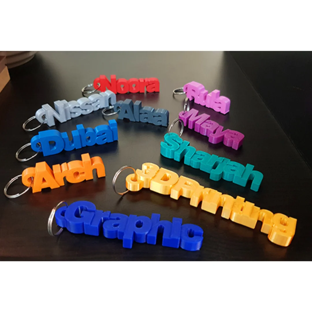 Collection of 3D printed name keychains with raised lettering and metal split rings.