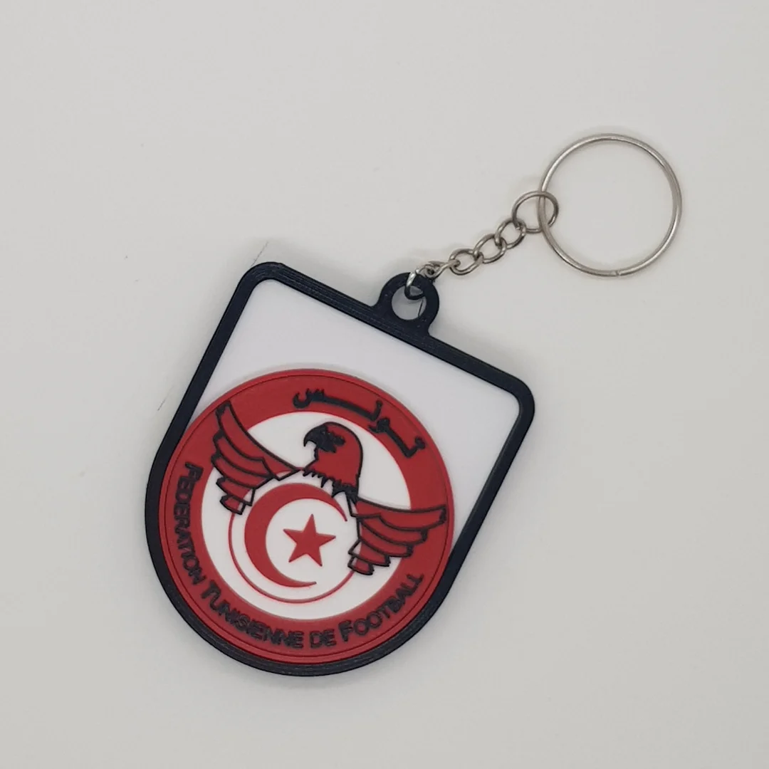 Front view of a Tunisia football crest keychain with its chain and key ring.