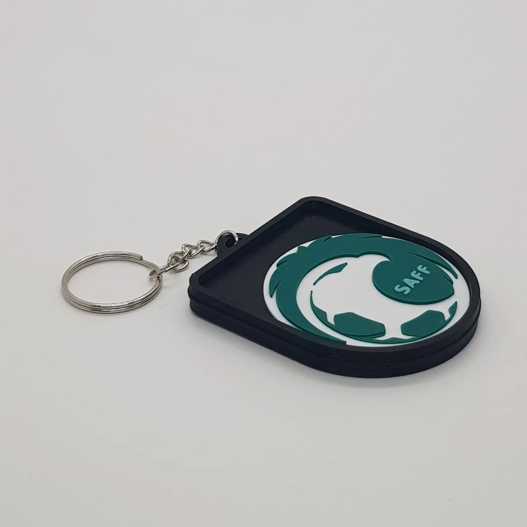 Angled front view of a Saudi Arabia football keychain showing the raised crest and metal key ring.