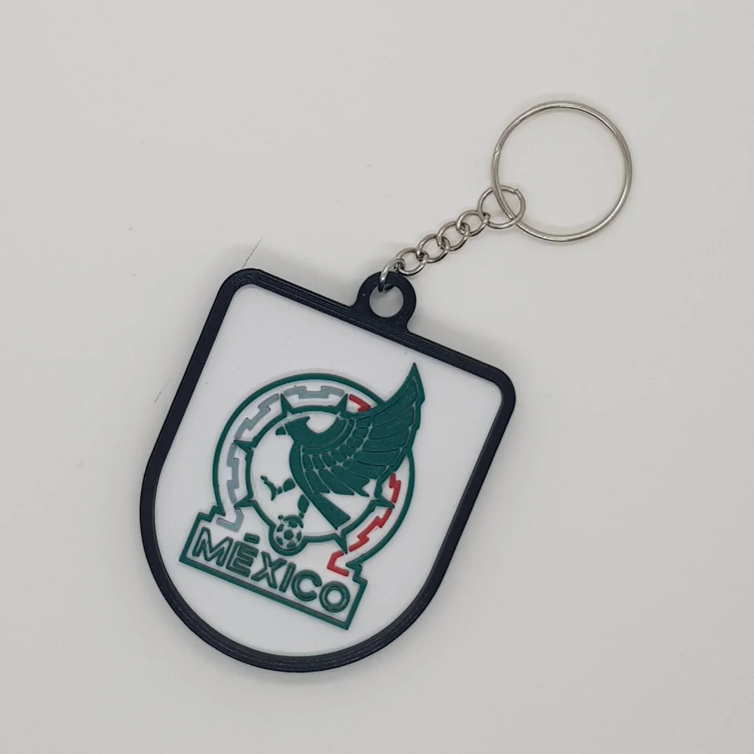 Front view of the Mexico football crest keychain with its chain and key ring.