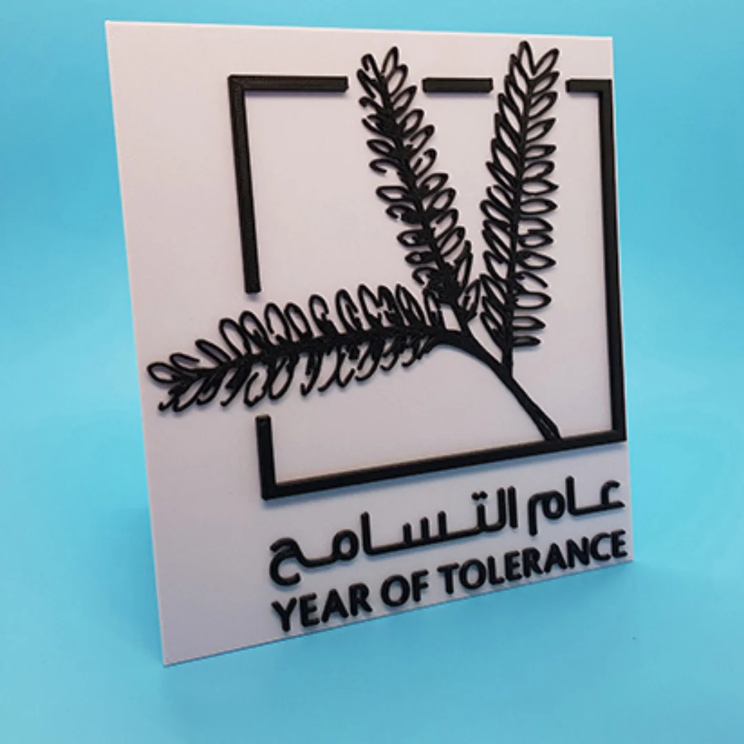 Angled view of a Year of Tolerance plaque with raised branch design and Arabic and English lettering.